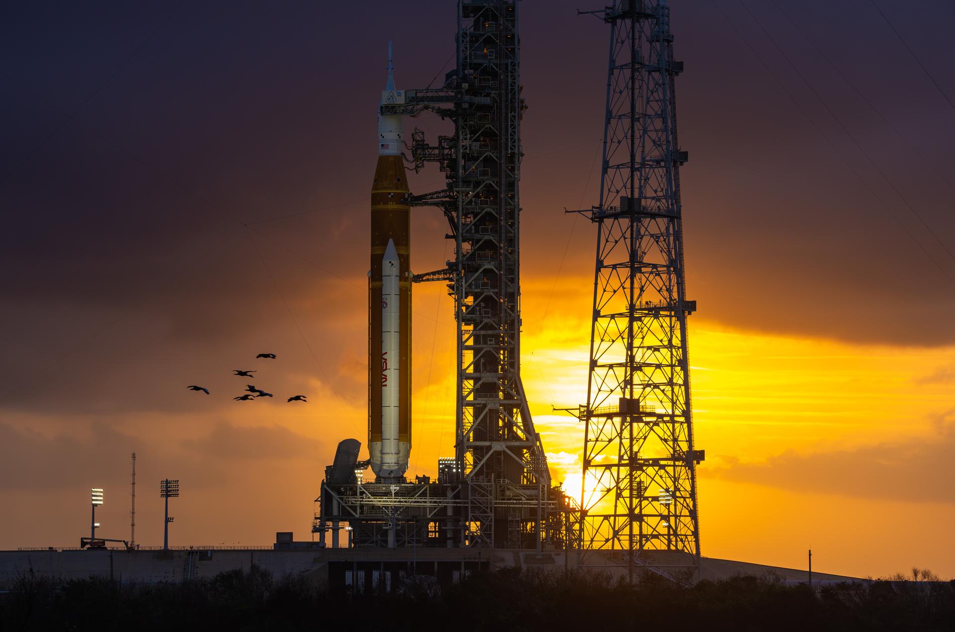 This image shows a sunset of NASA’s SLS (Space Launch System) and Orion spacecraft at NASA’s Kennedy Space Center. NASA's massive Crawler-Transporter, upgraded for the Artemis program, carried the powerful SLS rocket and Orion spacecraft on the Mobile Launcher from the Vehicle Assembly Building to Launch Pad 39B at Kennedy Space Center in preparation for the Artemis II mission.